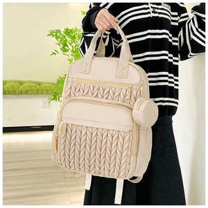 Detail of beige quilted backpack with V-shape texture and mini round pouch accessory