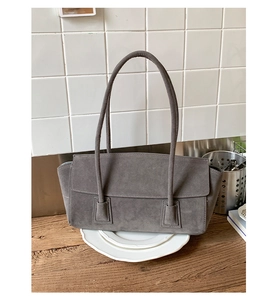 Detailed macro view of the minimalist grey suede shoulder bag with thin straps and flap