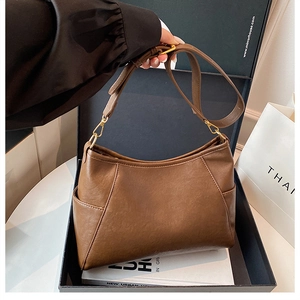 Detail of brown vintage leather handbag with gold hardware next to a gift box
