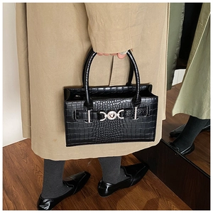 Detail of black crocodile texture handbag featuring silver heart buckle and sturdy handles