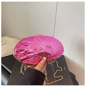 Close-up of pink mirror shell clutch bag with gold chain strap and wavy metallic texture