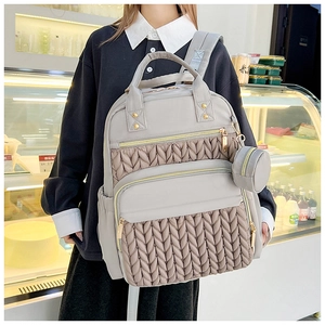 Detail view of large grey quilted backpack with matching round coin purse on a model
