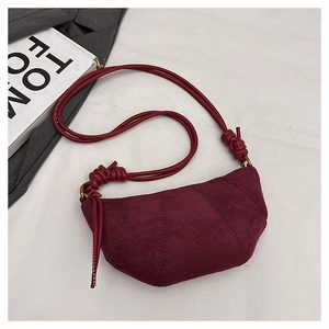 Dettaglio della borsa a mezzaluna in camoscio bordeaux con tracolla annodata e metallo vintage