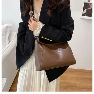 Close-up of brown vintage leather shoulder bag with adjustable strap and metal hardware