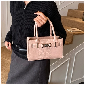 Macro detail of pink crocodile pattern leather handbag with golden lion buckle