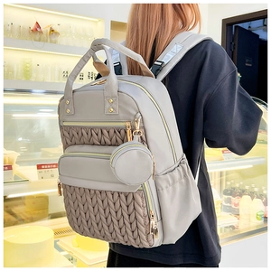 Detail of grey quilted backpack with matching small round coin purse and gold zippers