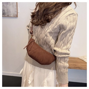 Dettagli di una borsa croissant in pelle scamosciata marrone con trapuntatura diagonale