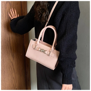 Detail showing pink crocodile-patterned handbag with silver buckle and crossbody strap