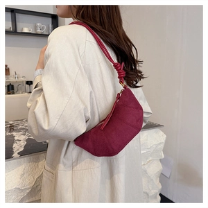 Dettaglio della borsa a mezzaluna bordeaux con texture scamosciata e nodo sulla tracolla