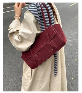 Sac à bandoulière chic en daim bordeaux porté par un mannequin pour un style urbain