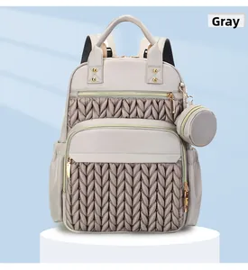 Detail of grey quilted backpack with V-shape stitching and small round coin purse charm