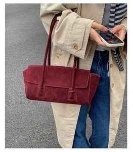 Detail of burgundy matte leather shoulder bag with sleek rectangular design and dual straps
