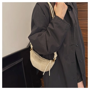 Dettaglio della borsa croissant beige minimalista con tessuto testurizzato e tracolla