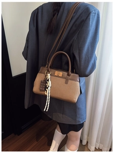 Detail view of a vintage canvas handbag with leather straps and chocolate-shaped charm