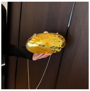 Close-up of golden shell-shaped evening bag with metallic pleated texture and chain