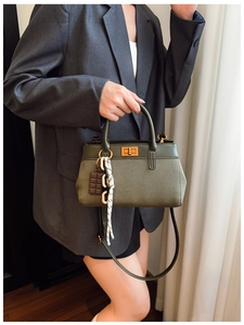 Detail view of dark green canvas handbag with leather trim and gold twist lock closure