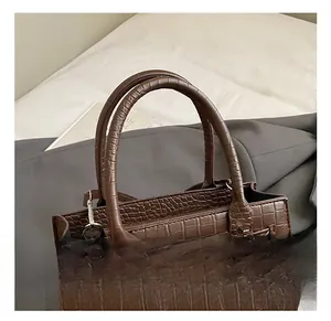 Close-up of the brown crocodile pattern texture and metal buckle on the handbag