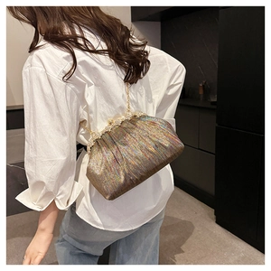 Detail of a ruffled sequin evening bag with pearl clasp and metal chain on a white shirt