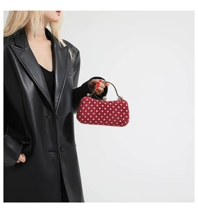 Mini sac rouge à pois avec poignée dorée et fermoir perle porté par un mannequin