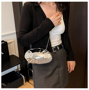 Silver mirror shell clutch with wavy metal texture and chain strap on a model