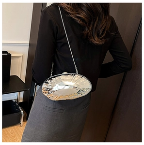 Detail of silver wavy shell clutch bag with metallic texture and sleek chain strap