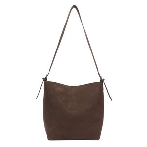 Minimalist coffee brown matte leather bucket bag with adjustable strap on white backdrop
