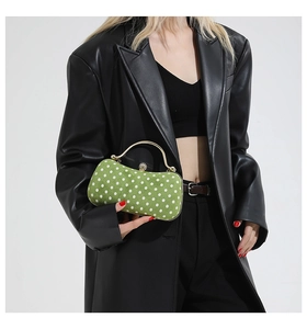 Close-up of green polka dot evening bag with gold metal handle and rhinestone clasp