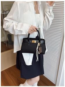 Detail of a vintage black leather handbag with gold twist lock and chic woven tassel