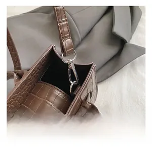 Macro detail of silver metal hook and dark brown crocodile pattern leather on the handbag