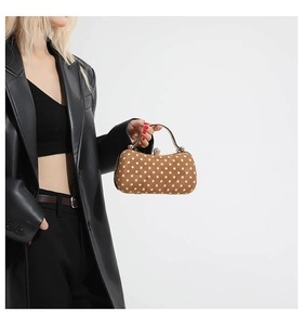 Vue détaillée du sac à main kaki à pois avec poignée en métal porté sur tenue noire