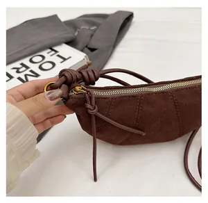 Dettaglio della borsa croissant in pelle scamosciata marrone con cerniera oro e nodo spalla