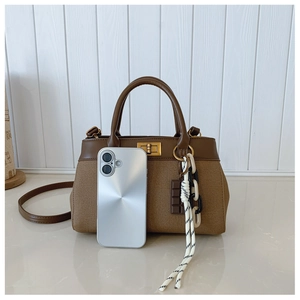 Brown canvas leather tote with gold hardware and phone for size reference
