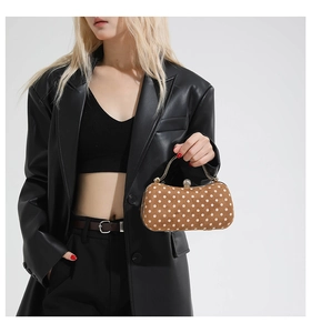 Close-up of brown polka dot evening bag with gold handle and diamond buckle detail