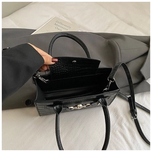 Top view of open black crocodile embossed box bag showing interior storage on grey blazer