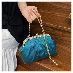 Detail of dark teal glitter evening clutch with gold metal frame and rhinestone trim