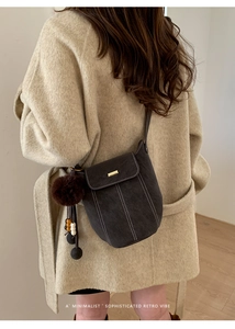 Detail of retro grey bucket bag with white contrast stitching and plush ball charm