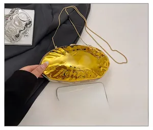 Detail view of mini gold acrylic shell bag with metallic texture and removable chain strap