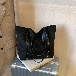 Quilted black tote bag with silver studs on luggage for travel and commuting