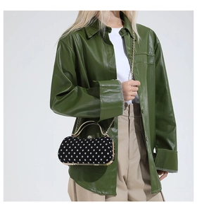 Close-up of model wearing black polka dot mini crossbody bag with gold chain and metal handle