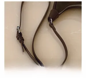Detail of adjustable dark brown leather strap with silver buckle and fine stitching