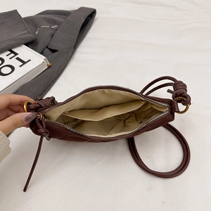 Dettaglio dell'interno della borsa a tracolla in camoscio marrone con cerniera e tasca
