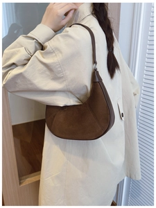 Detail of brown suede crescent bag with smooth leather strap and silver buckle hardware