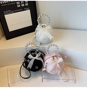 Three plush spherical handbags with satin bows and elegant beaded handles on display