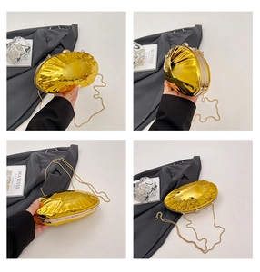 Detailed close-up of shell-shaped gold evening clutch with reflective metal finish and chain