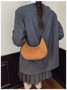 Hobo crescent bag detail showing caramel suede texture and leather piping on shoulder strap
