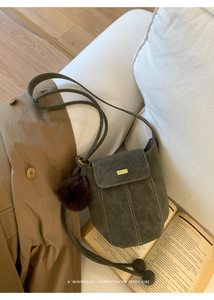 Detail view of dark green suede bucket bag with contrast stitching and decorative gold metal buckle