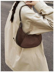 Detail view of coffee suede crescent bag with smooth leather strap on a model shoulder
