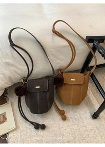 Close-up of vintage bucket bags in coffee and khaki with tassels and plush pom-pom charms