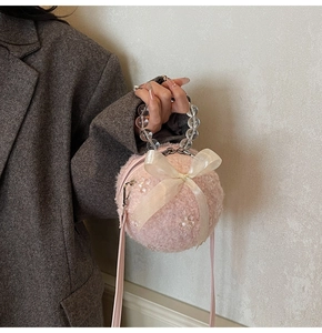 Detail of pink faux fur ball bag featuring a white organza bow and beaded handle
