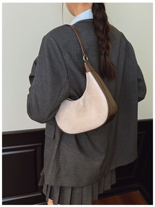 Detail view of a suede crescent hobo bag with vintage contrast leather stitching and strap